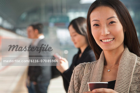 Young Woman Waiting on Train Platform with Coffee