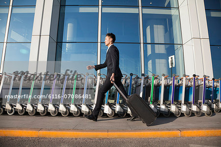 Traveler walking fast next to row of luggage carts at airport