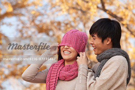 Young Man Covering a Young Woman's Eyes with Hat
