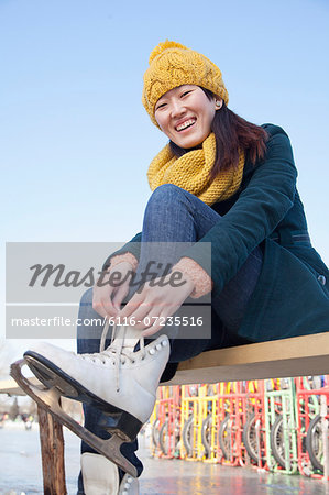 Young Woman Tying Ice Skates Outside