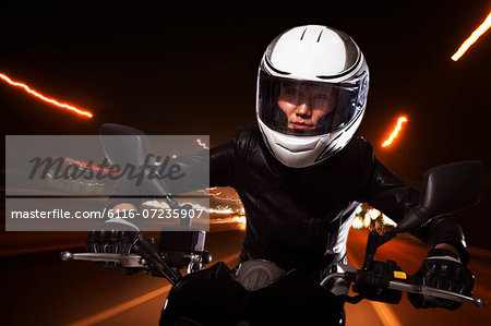 Young woman riding a motorcycle through the streets of Beijing, light trails