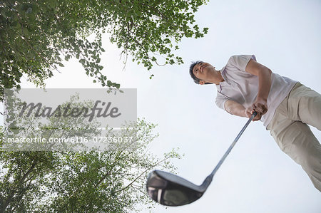 Low angle view of man getting ready to hit the golf ball on the golf course