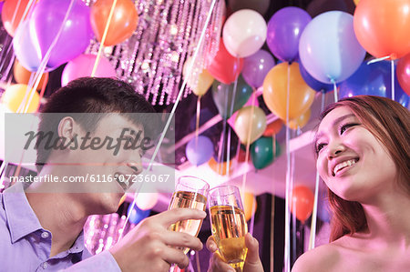 Two friends celebrating, toasting with champagne, nightclub in Beijing, balloons in the background