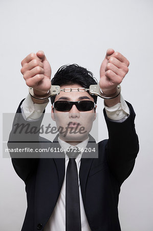 Cool businessman with sunglasses in handcuffs, studio shot