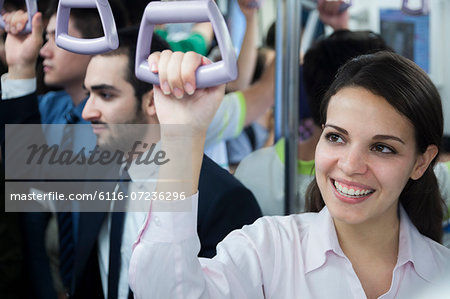 Portrait of smiling young businesswoman standing on the subway, looking away