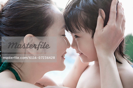 Smiling mother and son embracing and holding head by the pool