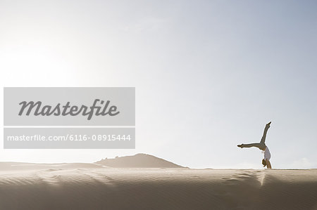 Woman doing handstand in desert