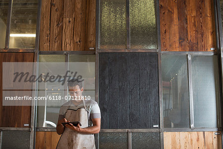 A Young Man In A Workshop. Using A Digital Tablet To Keep Records And Photograph Objects.