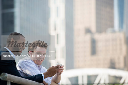 Summer. Two Men Looking At A Smart Phone, Texting And Photo Messaging.