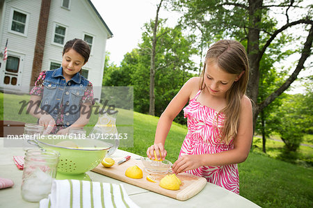 A Summer Family Gathering At A Farm. Two Girls Working Together, Making Homemade Lemonade.