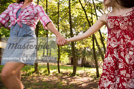 A Woman And A Young Girl Holding Hands And Running Along Under The Trees.