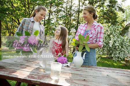 Three People Gathering Flowers And Arranging Them Together. A Mature Woman, A Teenager And A Child.