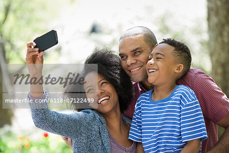 Two Adults And A Young Boy Taking Photographs With A Smart Phone.