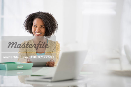 Business. A Woman Sitting At A Desk. Digital Tablet And Laptop, And Green Files.