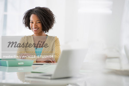 Business. A Woman Sitting At A Desk. Digital Tablet And Laptop, And Green Files.
