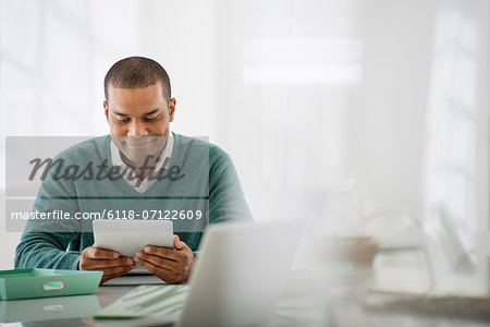 Business. A Light Airy Office Environment. A Man Sitting Holding A Digital Tablet.