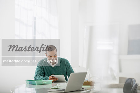 Business. A Light Airy Office Environment. A Man Sitting Holding A Digital Tablet.