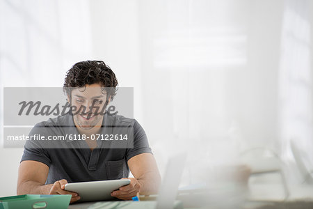 Business. A Light Airy Office Environment. A Man Sitting Holding A Digital Tablet.