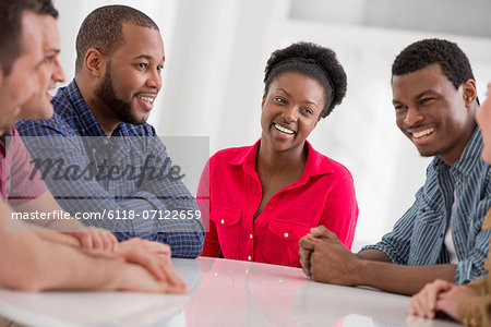 Office. A Group Of Four People, Two Men And Two Women Seated Talking.