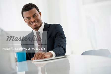 Office Interior. A Man In A Suit With A Cup Of Coffee. A Digital Tablet On The Table.