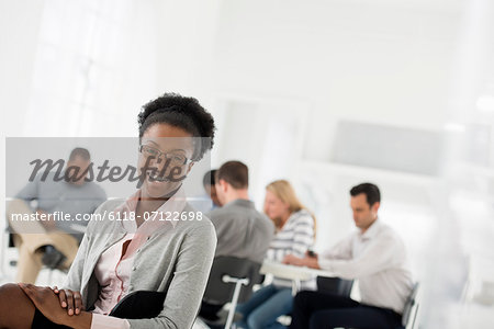 Office Interior. A Group Of People Meeting. One Person Looking Over Her Shoulder And Away From The Group.