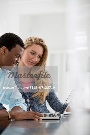 Office Interior. A Couple At A Table Using A Laptop. Office Interior. A Couple At A Table Using A Laptop.