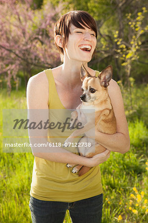 Young Woman In Grassy Field In Spring Holding A Dog