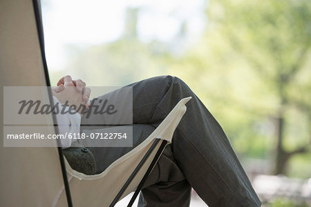 City Life. A Man Sitting In A Canvas Camping Chair In The Park.