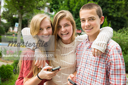 Three young people, two girls and a boy, posing and taking selfy