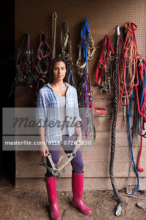 An organic farm in the Catskills. A person standing in a tack room in a stable.