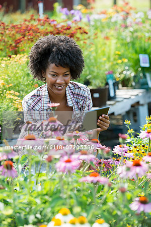A woman in a plant nursery surrounded by flowering plants and green foliage. A woman in a plant nursery surrounded by flowering plants and green foliage.