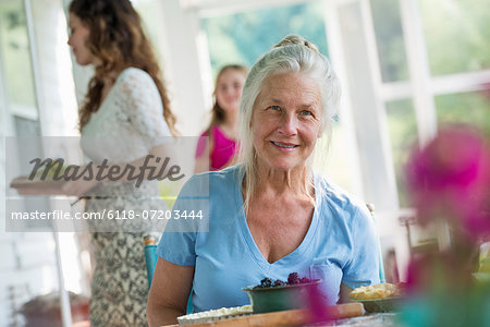 A family party in a farmhouse in the country in New York State. A mature woman holding bowl of fresh blackberries.