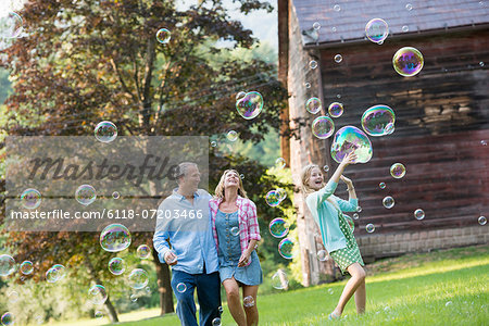 A family sitting on the grass outside a bar, blowing bubbles and laughing.