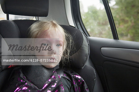 A young girl in a car seat in Halloween costume.