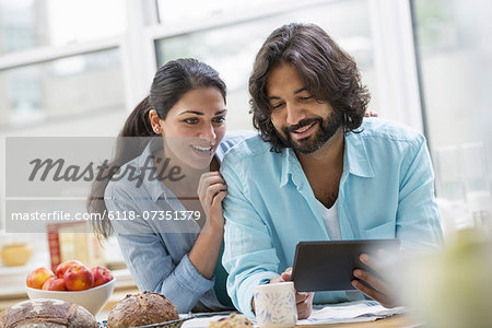 An office or apartment interior in New York City. A couple side by side by the breakfast bar. Food and fresh fruit.