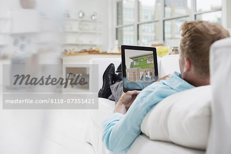 Business people. The office in summer. A man lying on a sofa, in comfort, in a quiet airy office environment. Using a digital tablet.