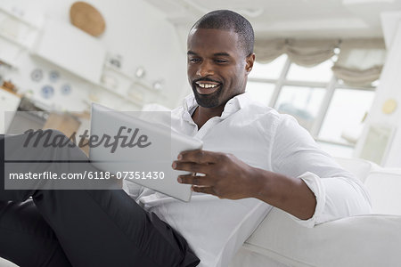 Business people. The office in summer. One person sitting comfortably in a quiet airy office environment. Using a digital tablet. Business people. The office in summer. One person sitting comfortably in a quiet airy office environment. Using a digital tablet.