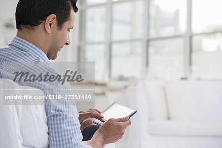 Professionals in the office. A light and airy place of work. A man seated using a digital tablet.