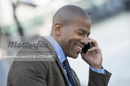 Business people in the city. Keeping in touch on the move. A man seated on a bench, making a call on his smart phone.