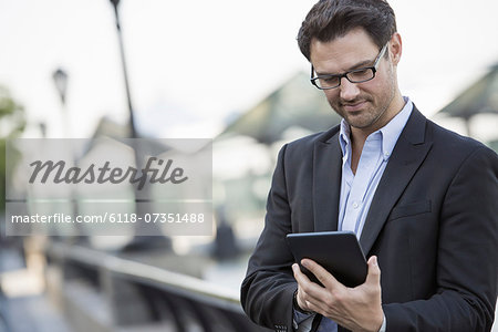 Business people outdoors in the city. Keeping in touch on the move. a man standing holding a digital tablet.