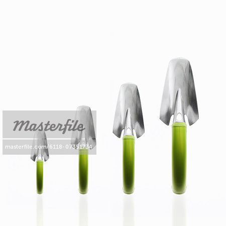 Four garden trowels with green handles and metal tops, in ascending size order.