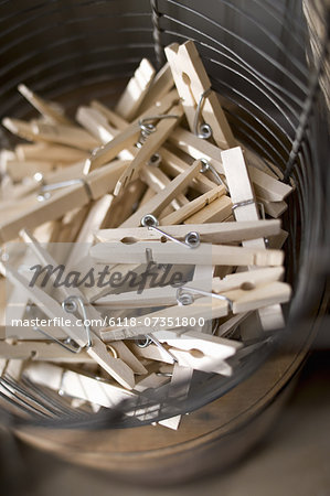 A wire basket with traditional wooden sprung clothes pegs or clothespins.