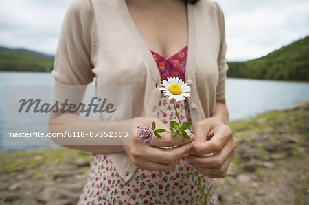 A woman in open countryside, by a mountain lake.