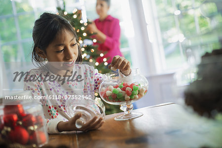 A young girl with a large glass jar of organic holiday gum drops.  Decorations for Christmas.