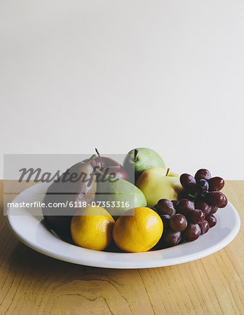 Plate of organic fresh fruit (tangerines, grapes, red bartlett pear, green anjou pears apples),