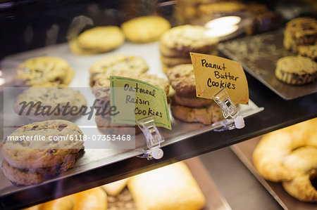 A tray of cookies, biscuits and baked goods on the counter at a coffee shop. Labels. Freshly home baked snacks.