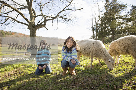 Two children at an animal sanctuary, in a paddock with sheep.