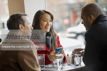 City life. A group of people on the go,using mobile phones, and talking to each other. In a coffee shop.