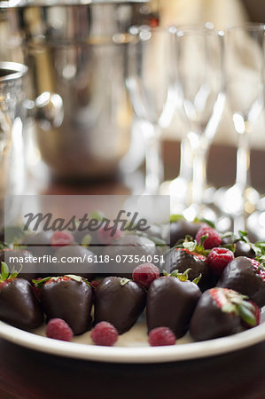 Wedding dessert. Plate of hand-dipped organic strawberries, fruit in artisinal handmade chocolate with raspberry garnish.