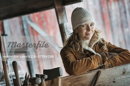 An organic farm in upstate New York, in winter. A woman in a sheepskin coat. A row of hand tools hanging on a post.